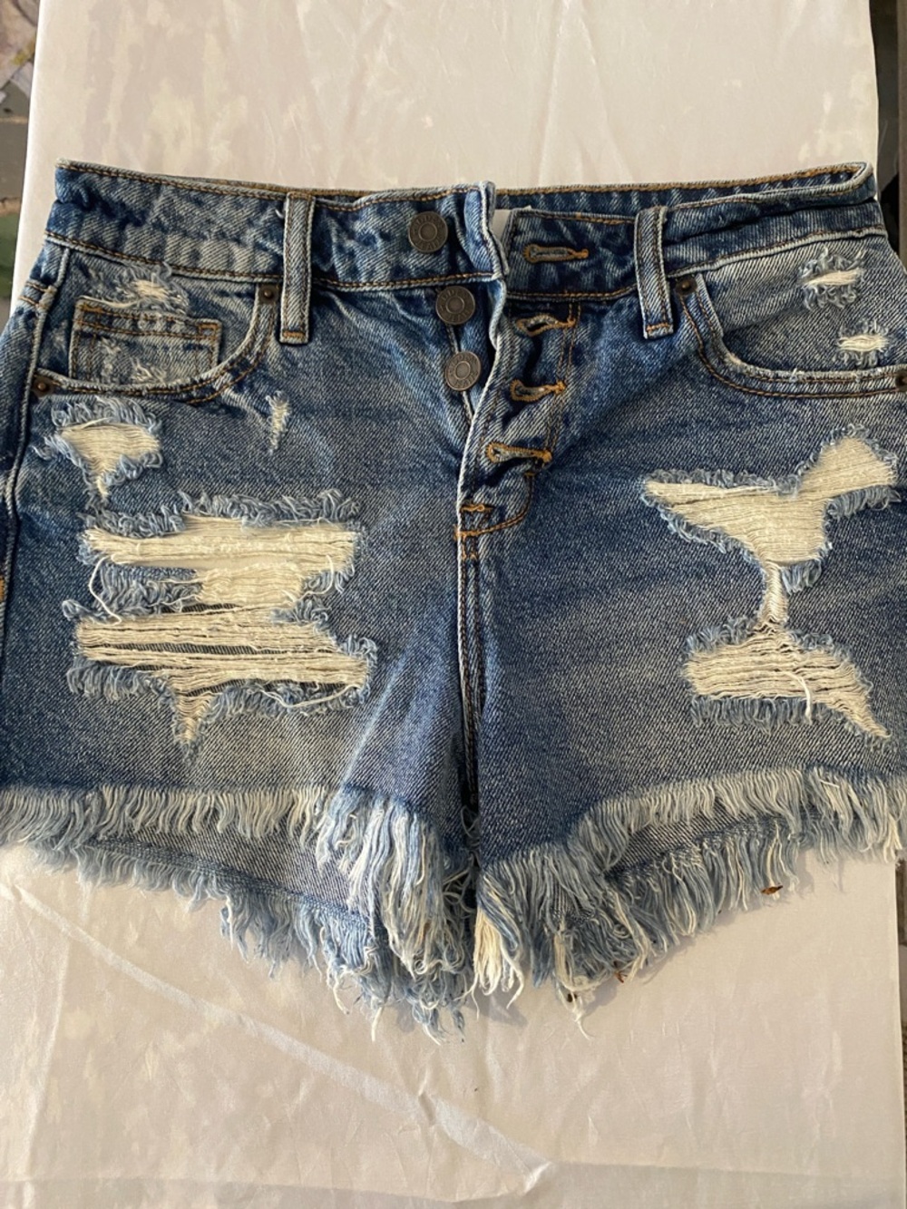 High-Rise Distressed Denim Shorts in Light Blue